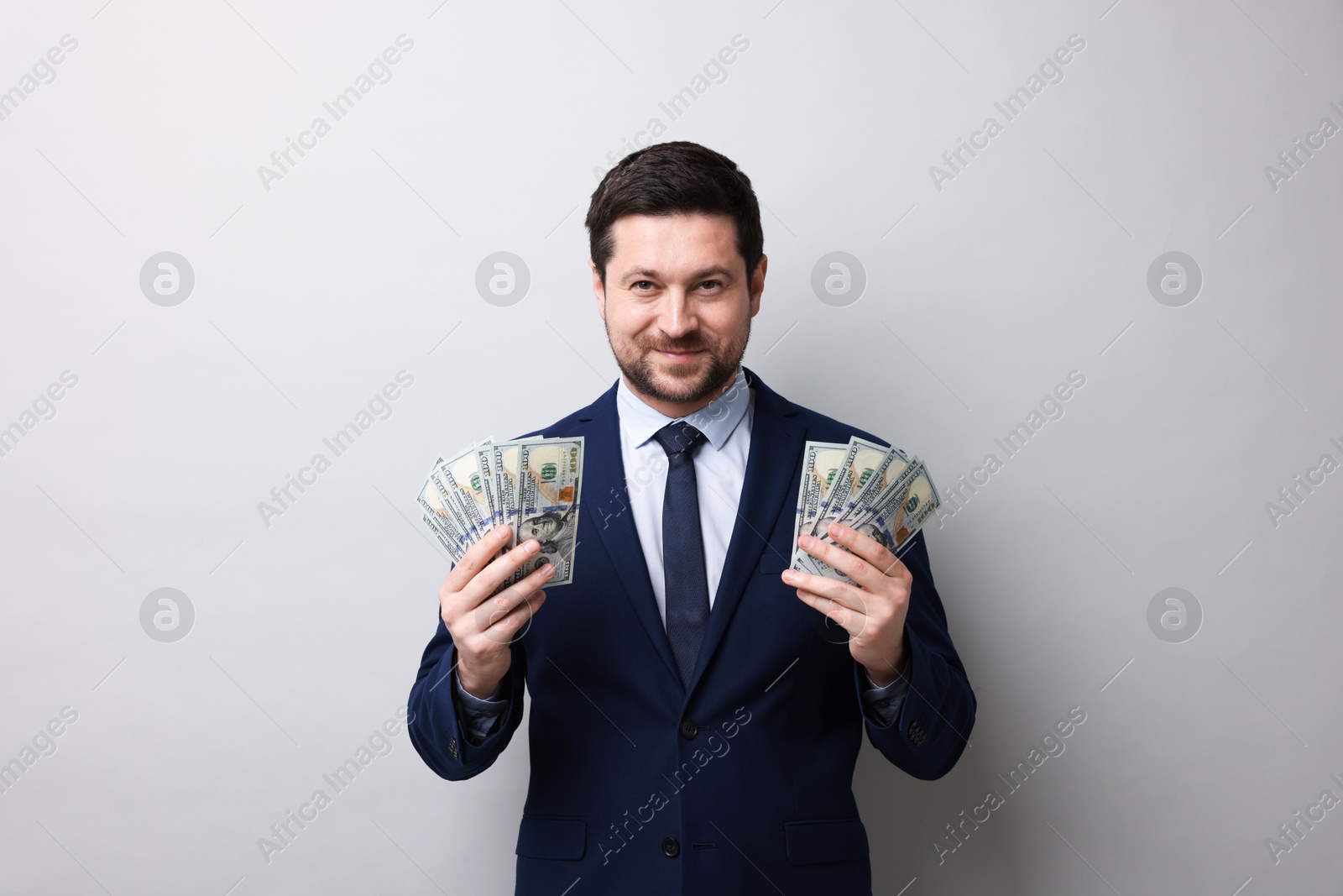 Greedy banker with dollar banknotes on grey background Photo of Greedy banker with dollar banknotes on grey background