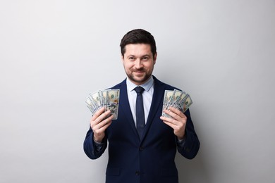 Photo of Greedy banker with dollar banknotes on grey background