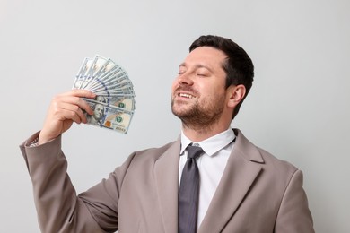Photo of Happy greedy banker waving money on grey background