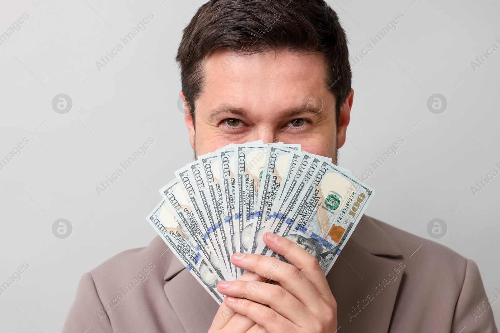 Greedy banker with dollar banknotes on grey background Photo of Greedy banker with dollar banknotes on grey background