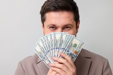 Photo of Greedy banker with dollar banknotes on grey background