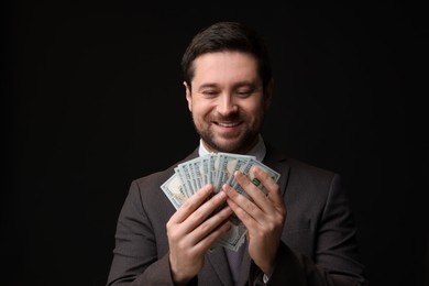 Photo of Happy greedy banker with dollar banknotes on black background