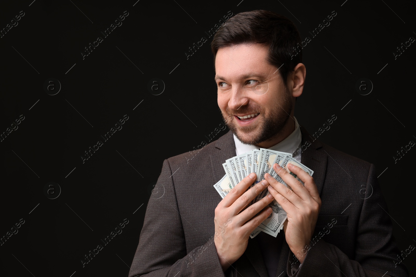 Happy greedy banker with dollar banknotes on black background. Space for text Photo of Happy greedy banker with dollar banknotes on black background. Space for text