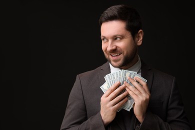 Photo of Happy greedy banker with dollar banknotes on black background. Space for text