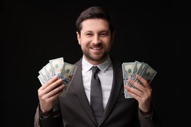 Photo of Happy greedy banker with dollar banknotes on black background