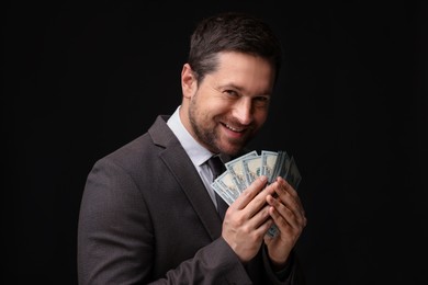 Photo of Happy greedy banker with dollar banknotes on black background