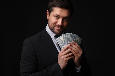 Photo of Greedy banker with dollar banknotes on black background