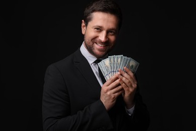 Photo of Happy greedy banker with dollar banknotes on black background
