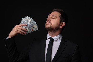 Photo of Greedy banker waving money on black background