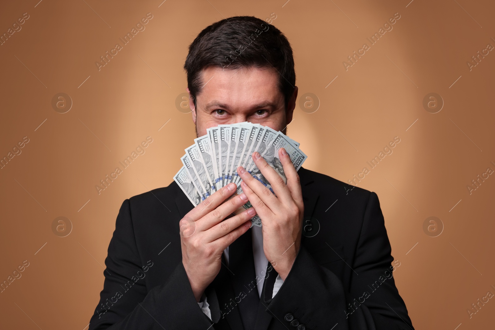 Greedy banker with dollar banknotes on golden background Photo of Greedy banker with dollar banknotes on golden background