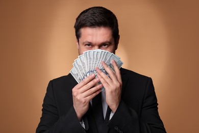 Photo of Greedy banker with dollar banknotes on golden background