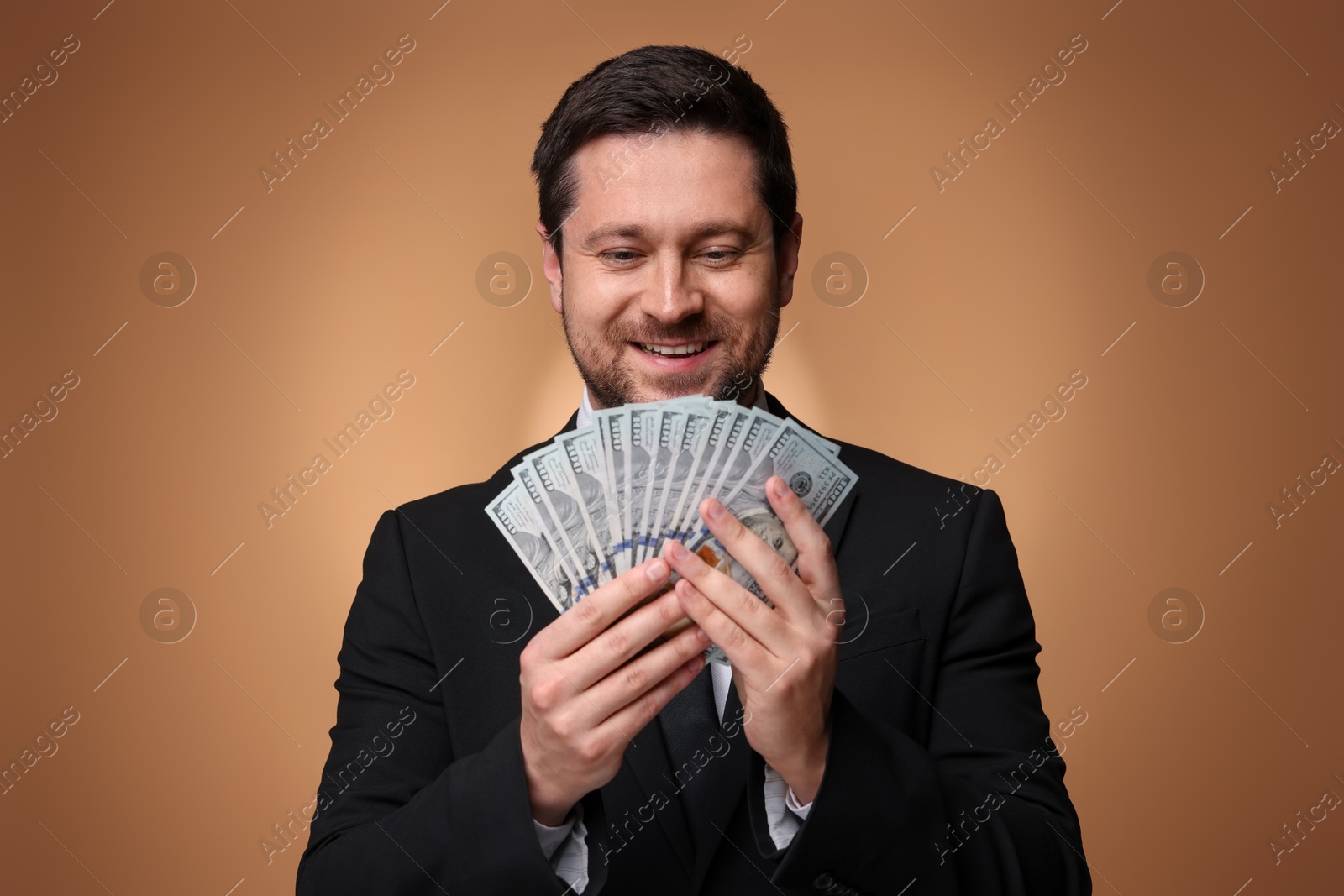 Happy greedy banker with dollar banknotes on golden background Photo of Happy greedy banker with dollar banknotes on golden background