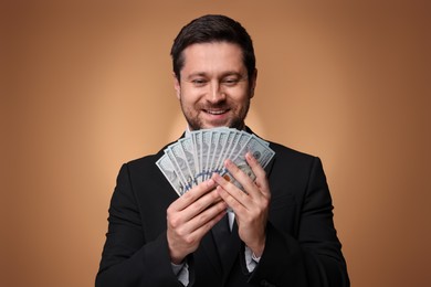 Photo of Happy greedy banker with dollar banknotes on golden background