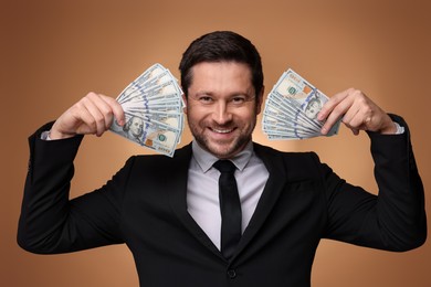 Photo of Happy greedy banker with dollar banknotes on golden background