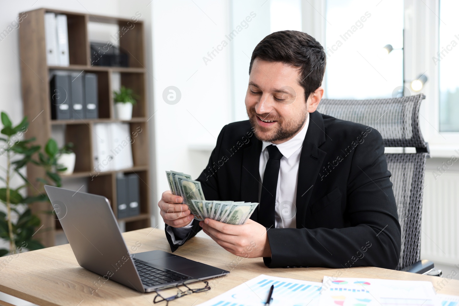Greedy banker counting money and smiling at table in office Photo of Greedy banker counting money and smiling at table in office