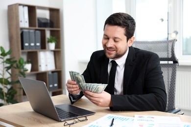 Photo of Greedy banker counting money and smiling at table in office