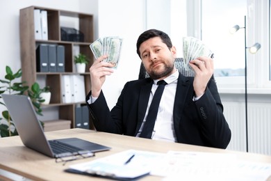 Photo of Greedy banker with dollar banknotes at table in office
