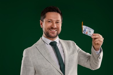 Photo of Happy greedy banker with burning dollar banknote on green background