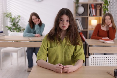 Photo of Bullying. Upset teenage girl at desk in school
