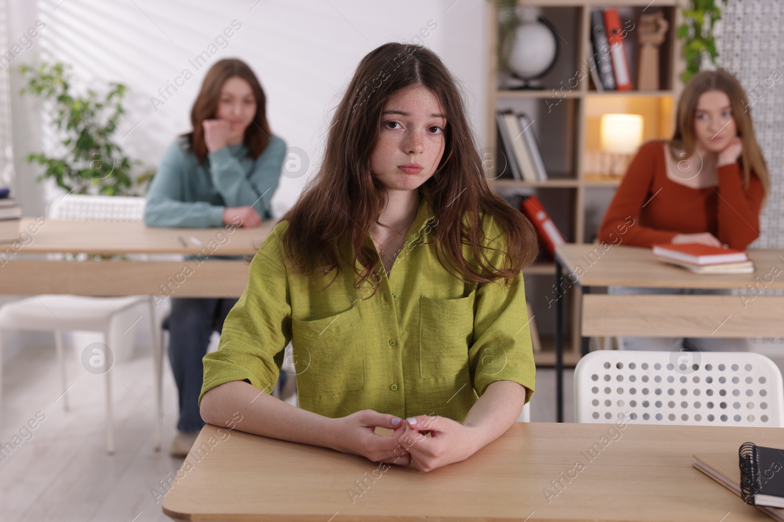 Photo of Bullying. Upset teenage girl at desk in school