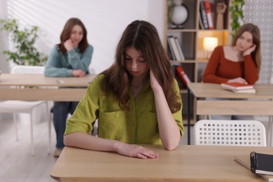 Photo of Bullying. Upset teenage girl at desk in school