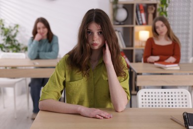 Photo of Bullying. Upset teenage girl at desk in school