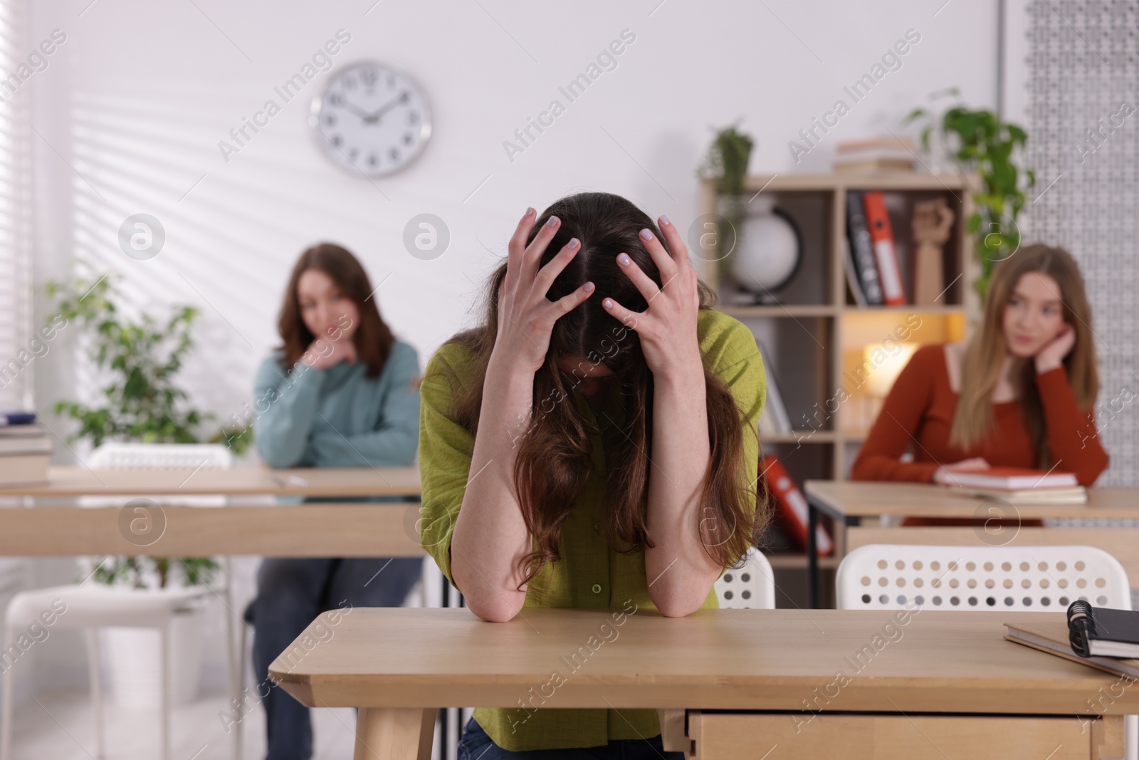 Bullying. Upset teenage girl at desk in school Photo of Bullying. Upset teenage girl at desk in school