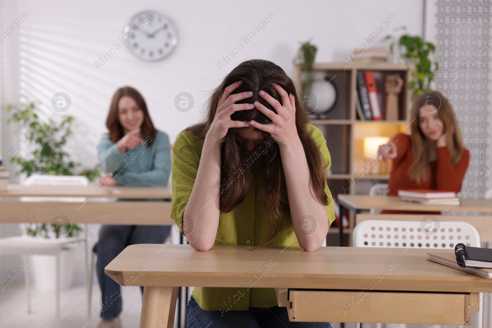 Photo of Bullying. Upset teenage girl at desk in school