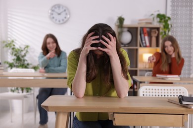 Photo of Bullying. Upset teenage girl at desk in school