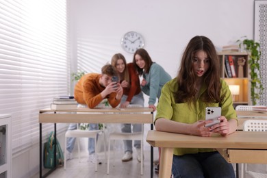 Photo of Teenage girl with smartphone suffering from bullying at school, selective focus