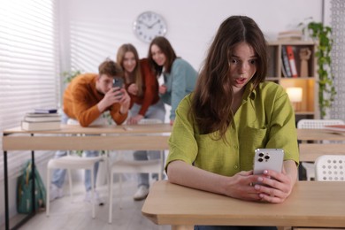Photo of Teenage girl with smartphone suffering from bullying at school, selective focus