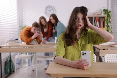 Photo of Teenage girl with smartphone suffering from bullying at school, selective focus
