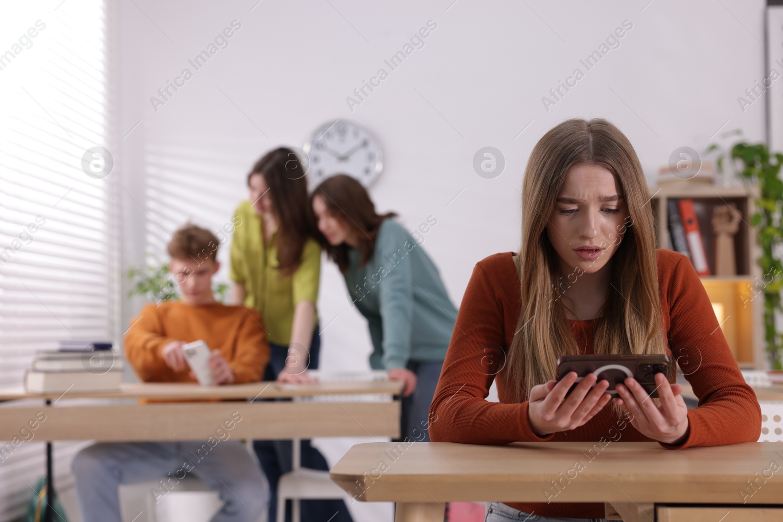 Teenage girl with smartphone suffering from bullying at school, selective focus Photo of Teenage girl with smartphone suffering from bullying at school, selective focus