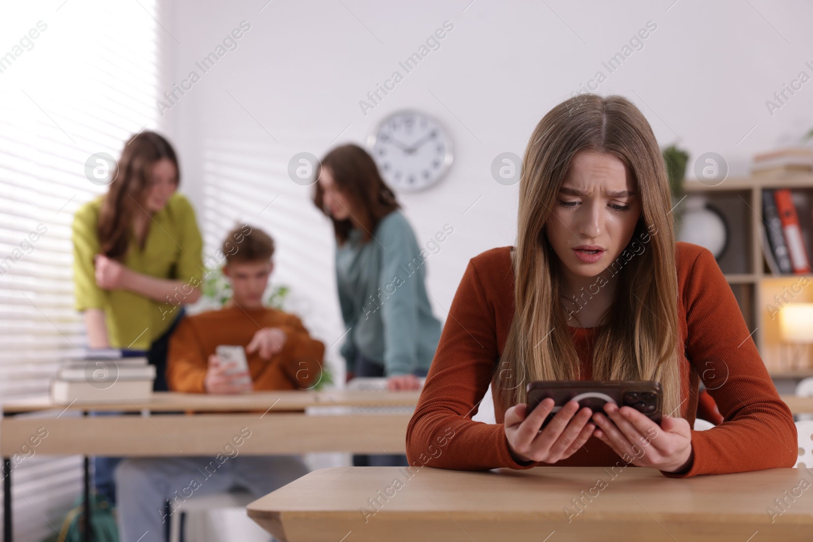 Teenage girl with smartphone suffering from bullying at school, selective focus Photo of Teenage girl with smartphone suffering from bullying at school, selective focus