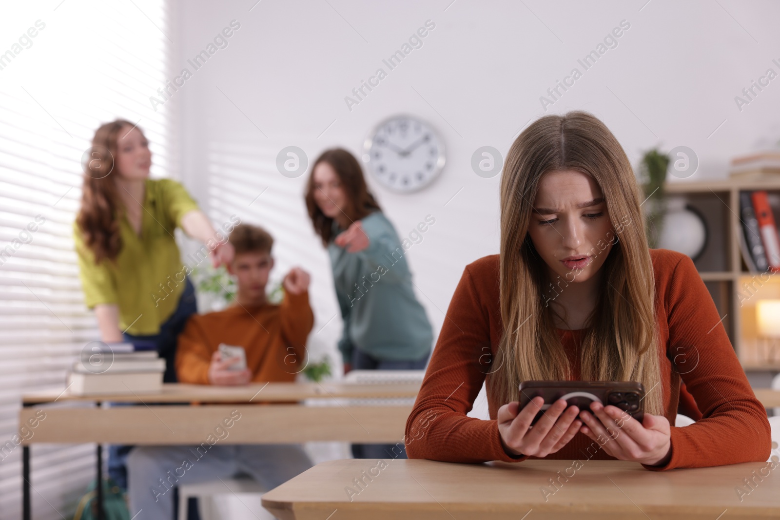 Teenage girl with smartphone suffering from bullying at school, selective focus Photo of Teenage girl with smartphone suffering from bullying at school, selective focus
