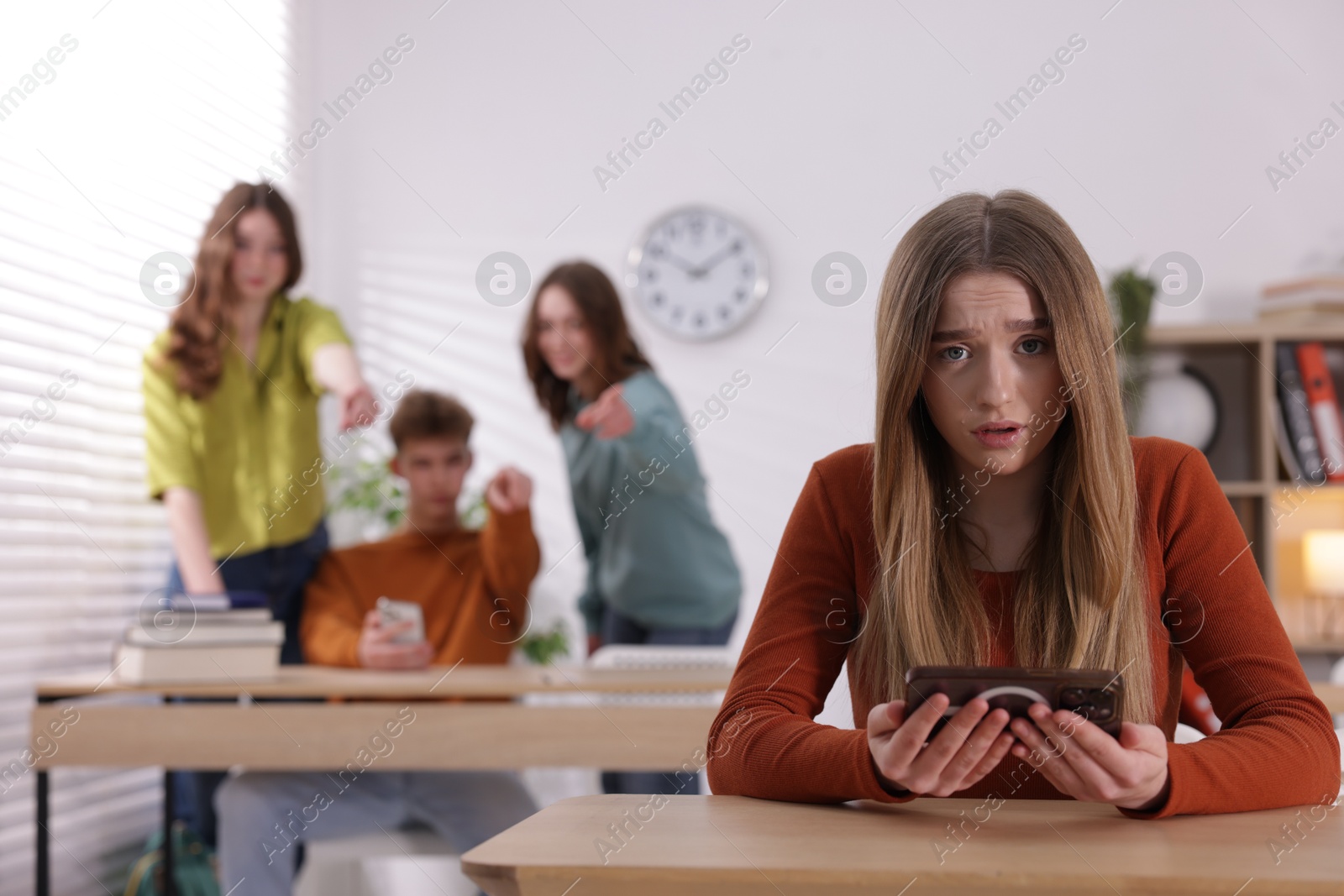 Teenage girl with smartphone suffering from bullying at school, selective focus Photo of Teenage girl with smartphone suffering from bullying at school, selective focus