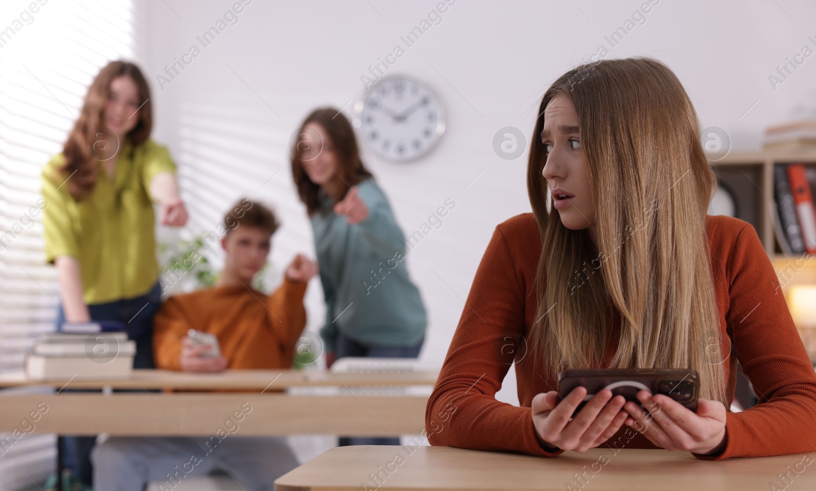 Teenage girl with smartphone suffering from bullying at school, selective focus Photo of Teenage girl with smartphone suffering from bullying at school, selective focus