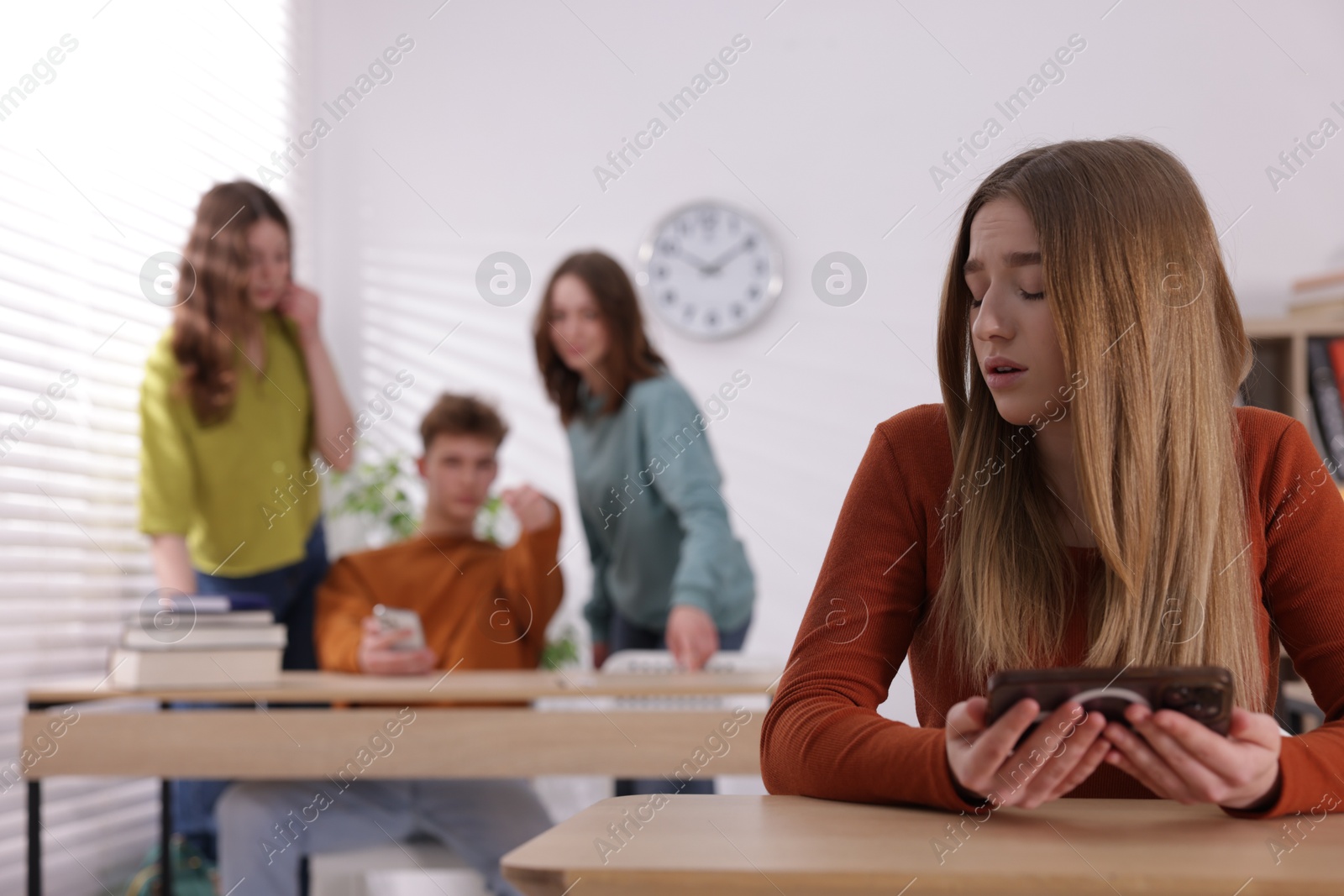 Teenage girl with smartphone suffering from bullying at school, selective focus Photo of Teenage girl with smartphone suffering from bullying at school, selective focus