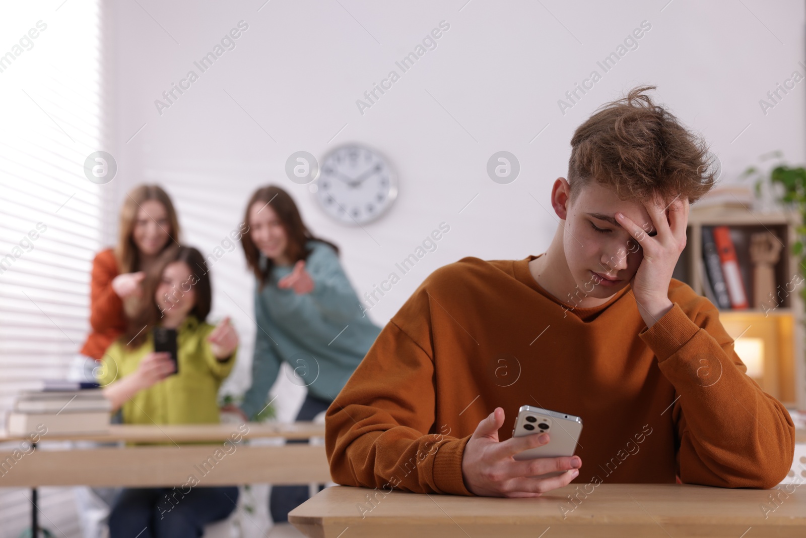 Teenage boy with smartphone suffering from bullying at school, selective focus Photo of Teenage boy with smartphone suffering from bullying at school, selective focus