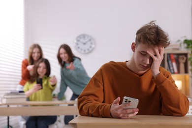 Photo of Teenage boy with smartphone suffering from bullying at school, selective focus