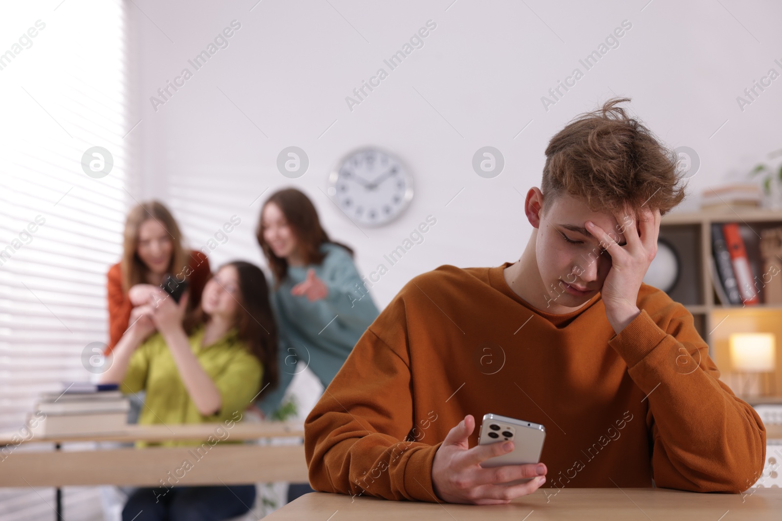 Teenage boy with smartphone suffering from bullying at school, selective focus Photo of Teenage boy with smartphone suffering from bullying at school, selective focus