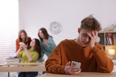 Photo of Teenage boy with smartphone suffering from bullying at school, selective focus