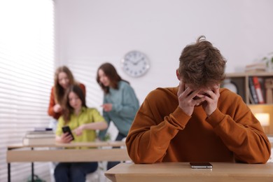 Photo of Teenage boy with smartphone suffering from bullying at school, selective focus