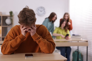 Photo of Teenage boy with smartphone suffering from bullying at school, selective focus
