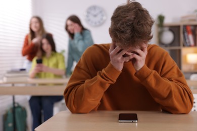 Photo of Teenage boy with smartphone suffering from bullying at school, selective focus
