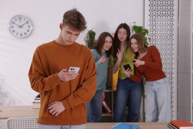 Photo of Teenage boy with smartphone suffering from bullying at school, selective focus