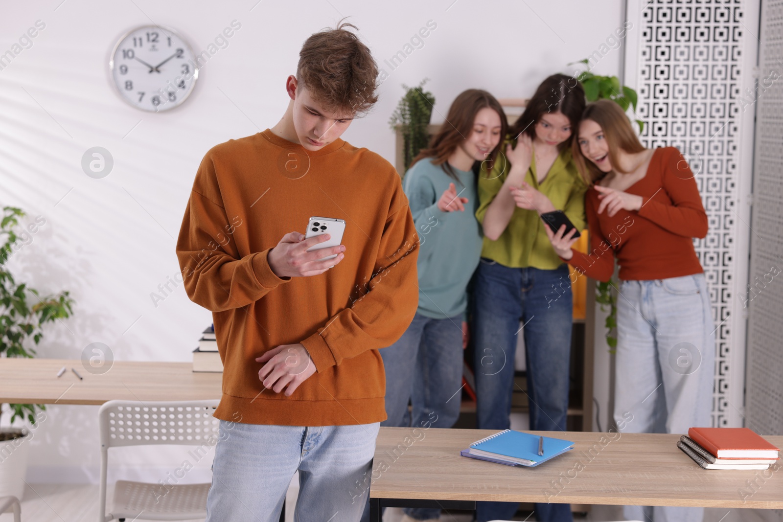 Teenage boy with smartphone suffering from bullying at school, selective focus Photo of Teenage boy with smartphone suffering from bullying at school, selective focus