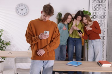 Photo of Teenage boy with smartphone suffering from bullying at school, selective focus
