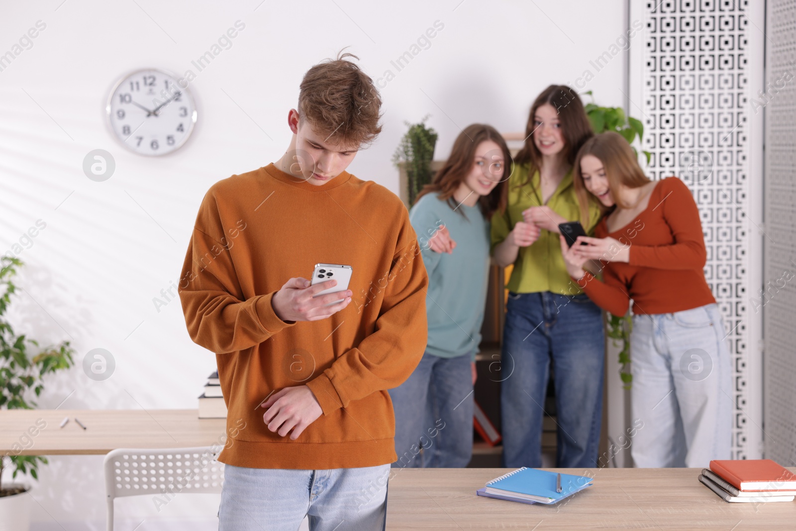 Teenage boy with smartphone suffering from bullying at school, selective focus Photo of Teenage boy with smartphone suffering from bullying at school, selective focus