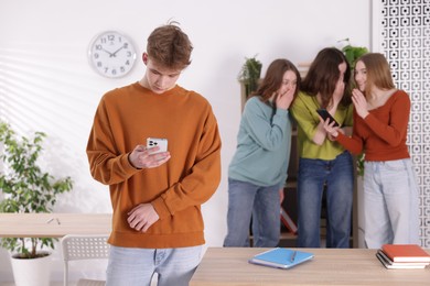 Photo of Teenage boy with smartphone suffering from bullying at school, selective focus